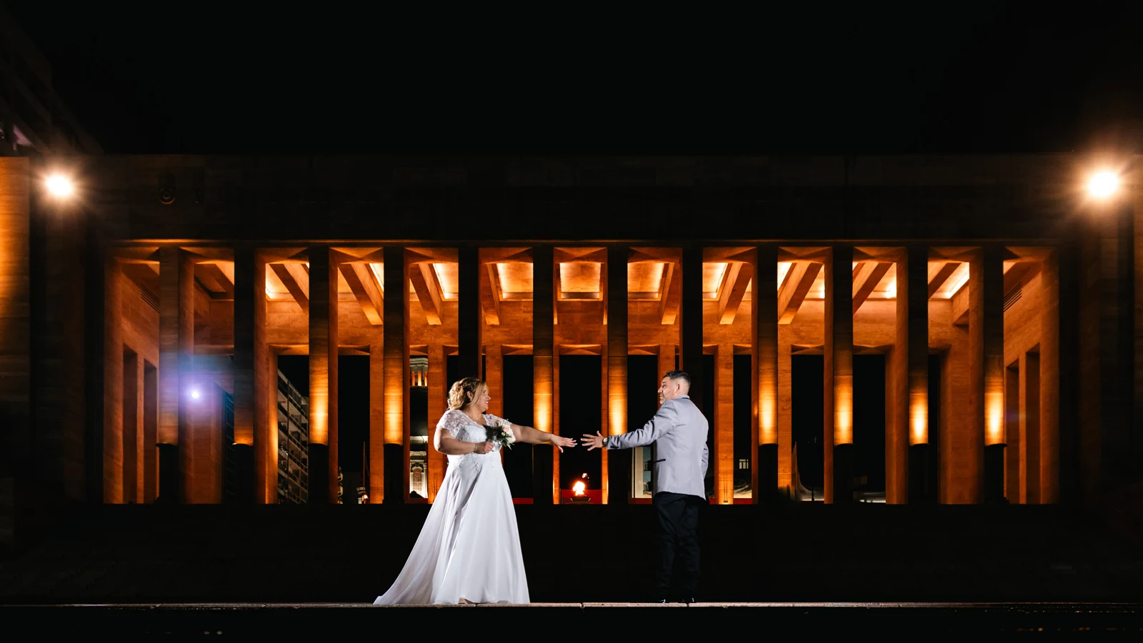 Novios frente a una arquitectura iluminada de noche