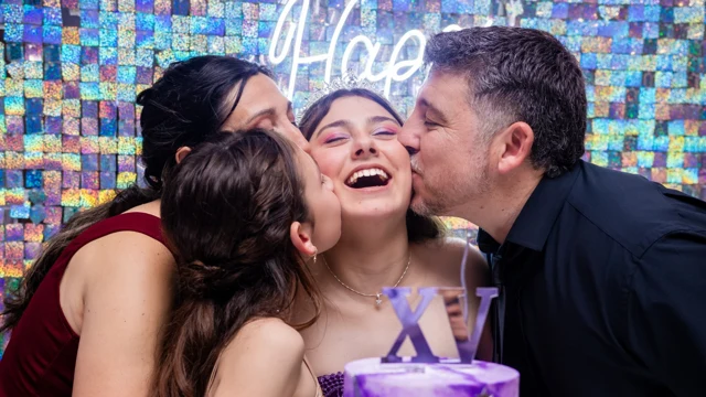 Quinceañera recibiendo besos de su familia